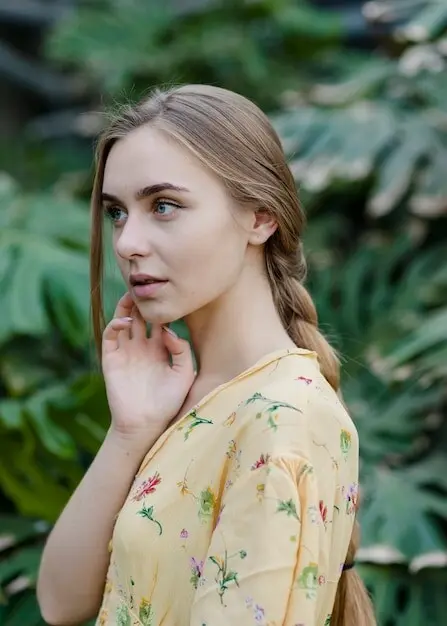 横からの視点で、温室内でポーズをとる若い女性。